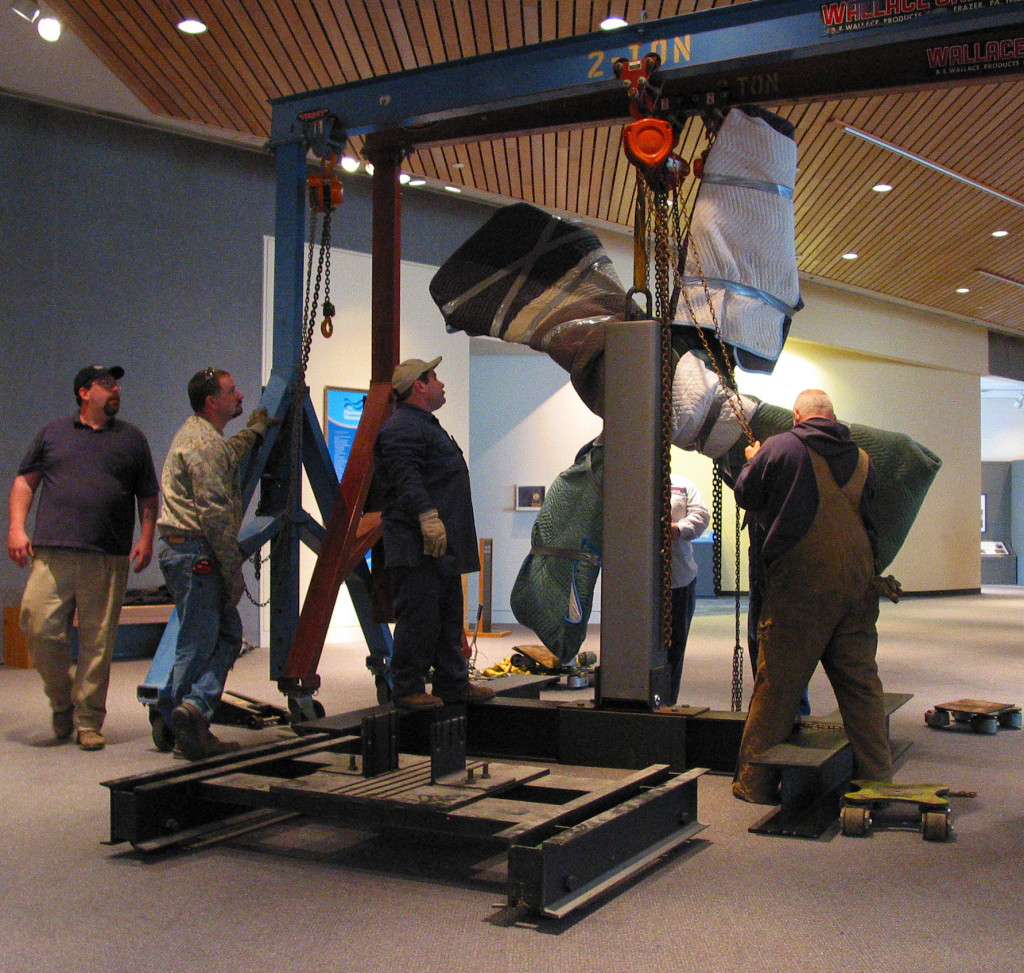 Conservation staff and rigging professionals prepare to move USS Monitor's 9-foot diameter cast iron propeller from its former location in the lobby of The Mariners' Museum to its current location within the USS Monitor Center at The Mariners' Museum.