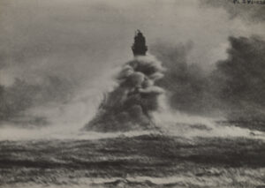 An ocean wave crashes against a lightouse, almost completely obscuring it.