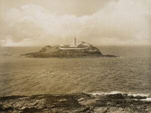 岛上灯塔的远处景色，周围是一堵低矮的石墙。