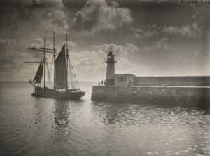 一个停靠在一座小灯塔附近的纵帆船的景色。